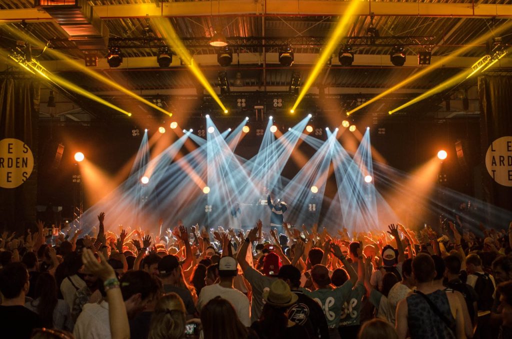group-of-people-inside-disco-house-167491 Energetic music concert scene with bright lights and a lively cheering crowd indoors.